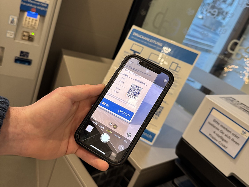 Jena library staff showing how to scan the Princh QR code from their phone.